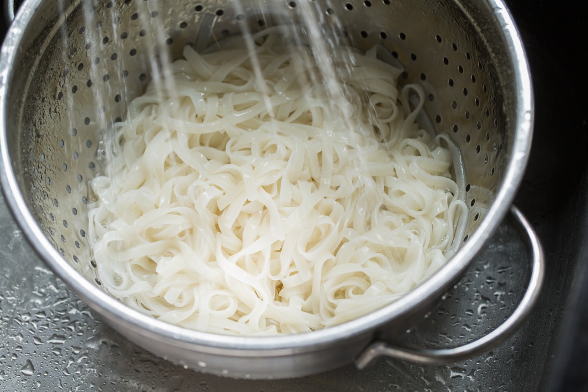 Rinsing rice noodles in a colander for Pad Thai.