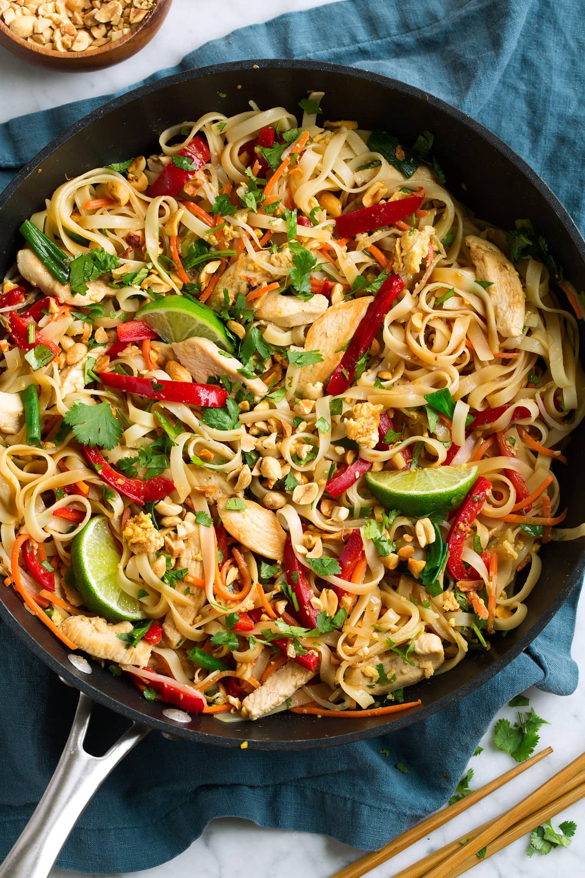 Pad Thai in a black wok with chicken and fresh vegetables.