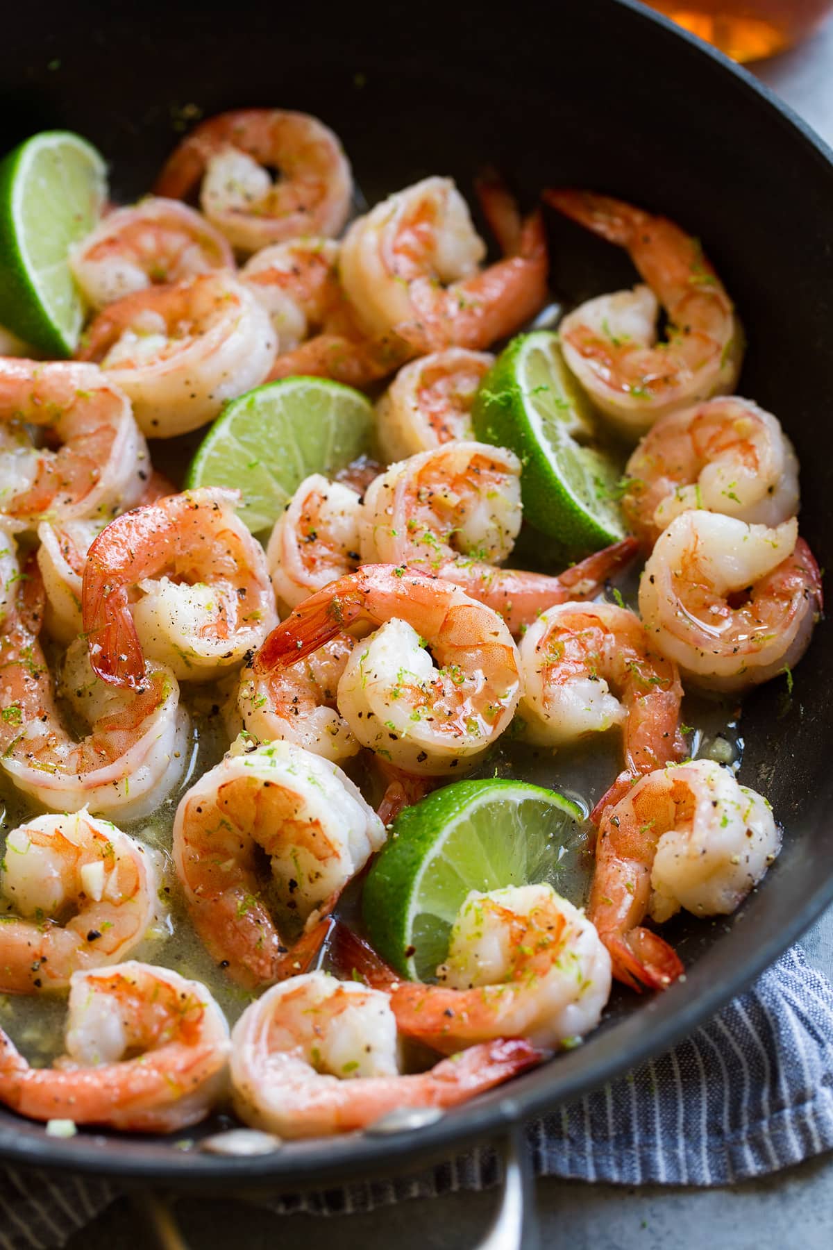 Close up image of shrimp with honey lime sauce in a black skillet.
