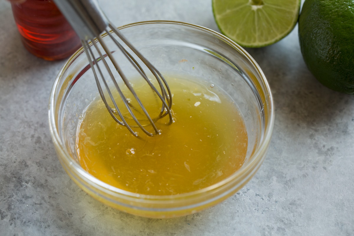 Showing how to make shrimp with sauce. Whisking together honey and lime in a glass mixing bowl.