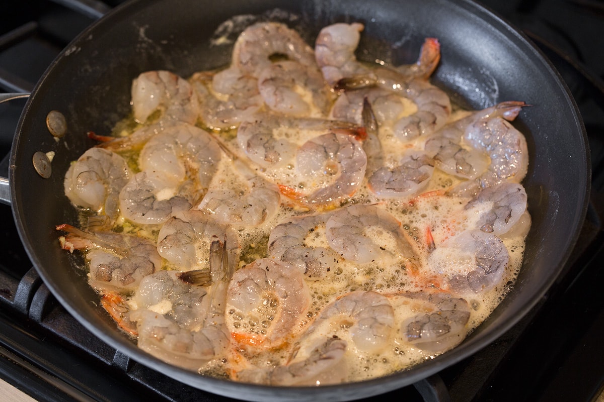 Cooking shrimp, honey and lime in skillet over stove top.