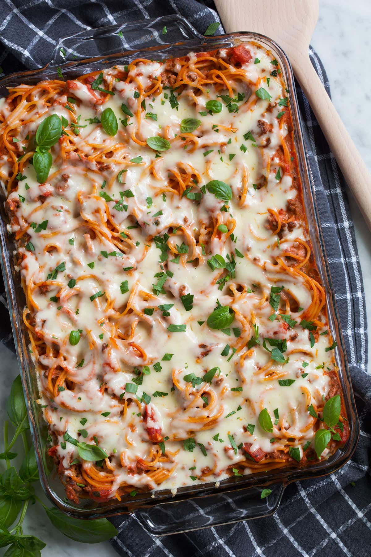 Baked Spaghetti in a glass baking dish set over a dark grey cloth.