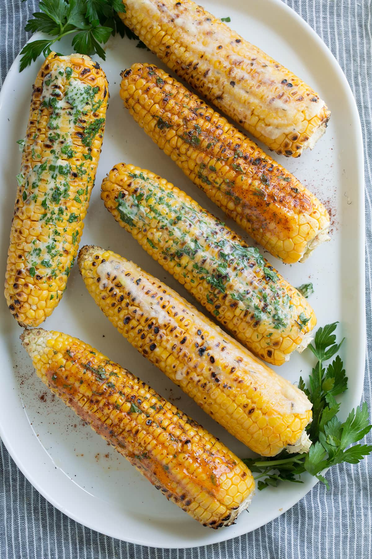 Six grilled corn on the cob rubbed with flavored butters.