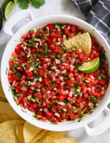 Overhead image of homemade pico de gallo in a white serving bowl with a side of tortilla chips.