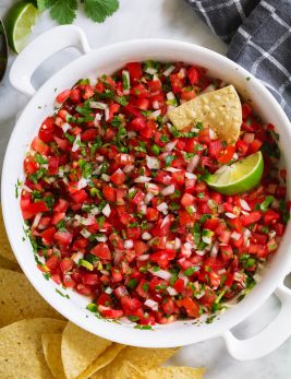 Overhead image of homemade pico de gallo in a white serving bowl with a side of tortilla chips.