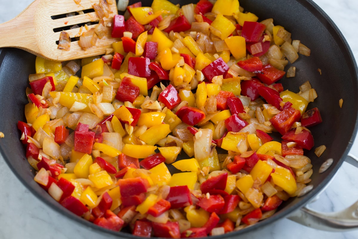 Sauteed red and yellow bell peppers, onion and garlic in a skillet. 