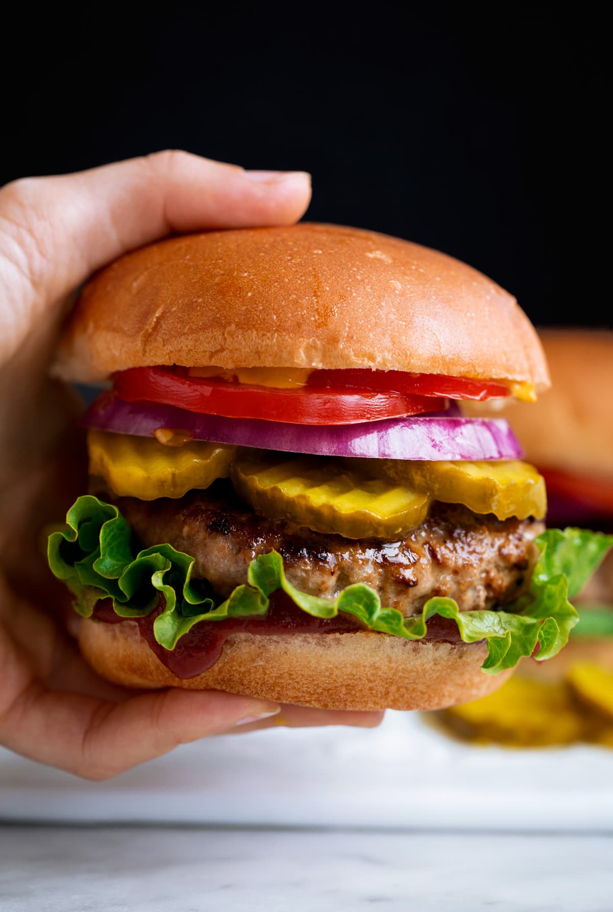 Close up image of hand holding a turkey burger on a bun.