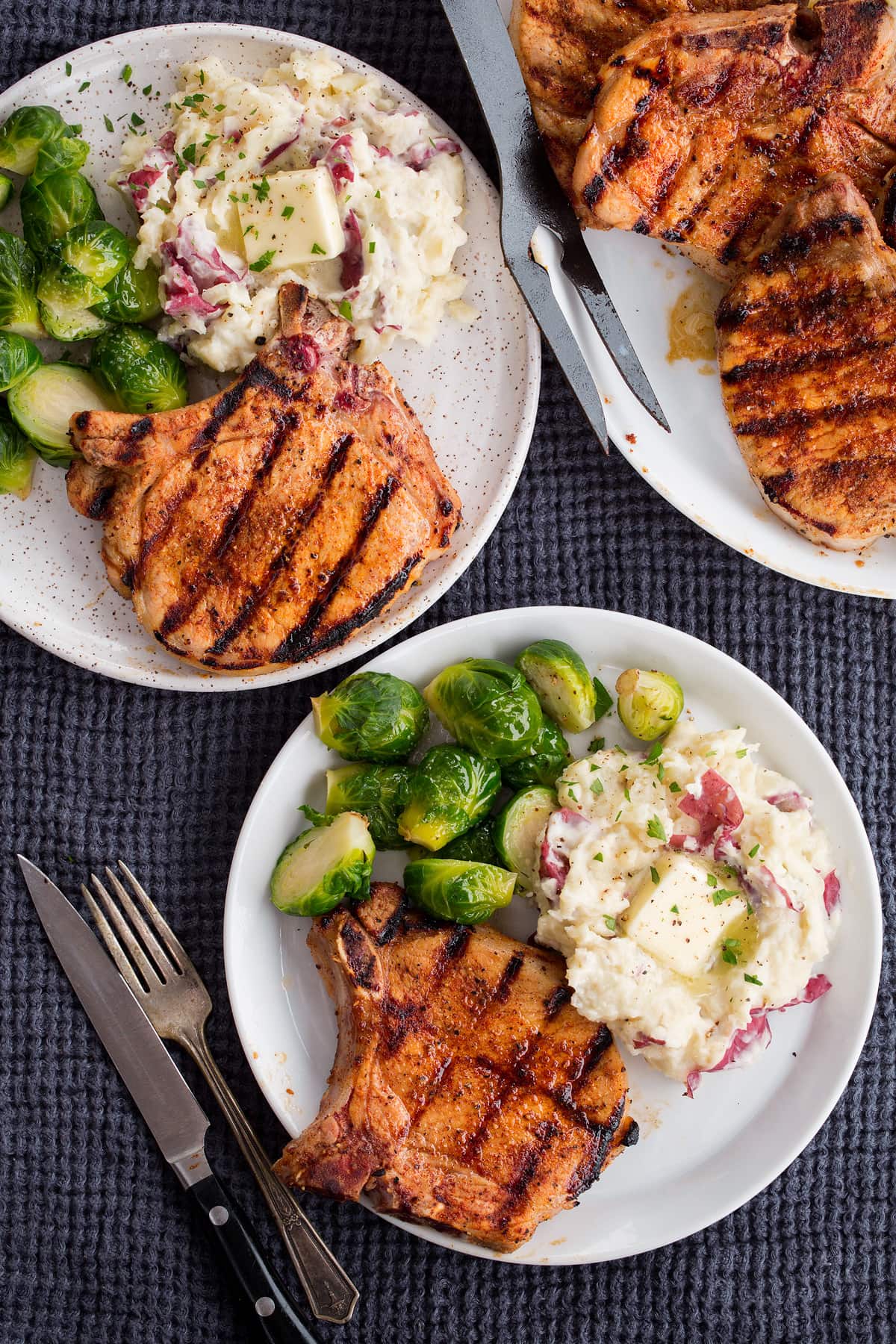 Showing serving suggestions sides to pair with grilled pork chops. Plate with pork chops, mashed potatoes and Brussesls sprouts.