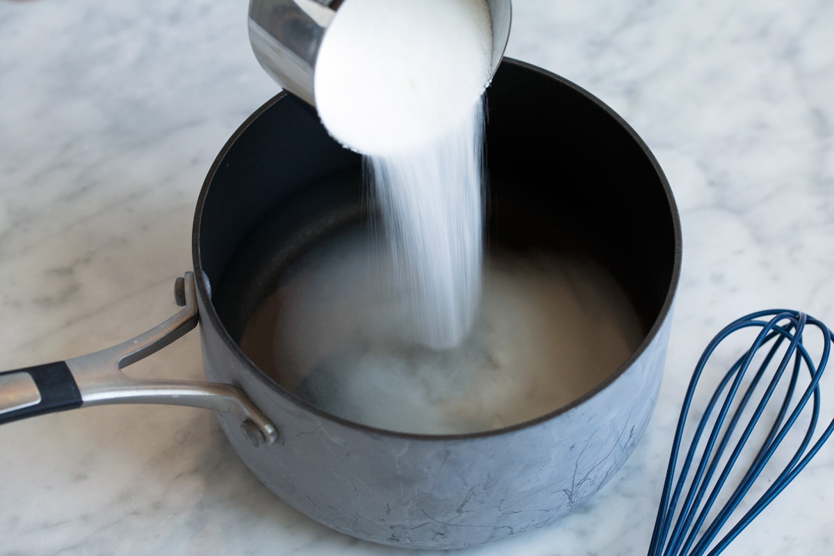 Adding sugar to water in a saucepan.