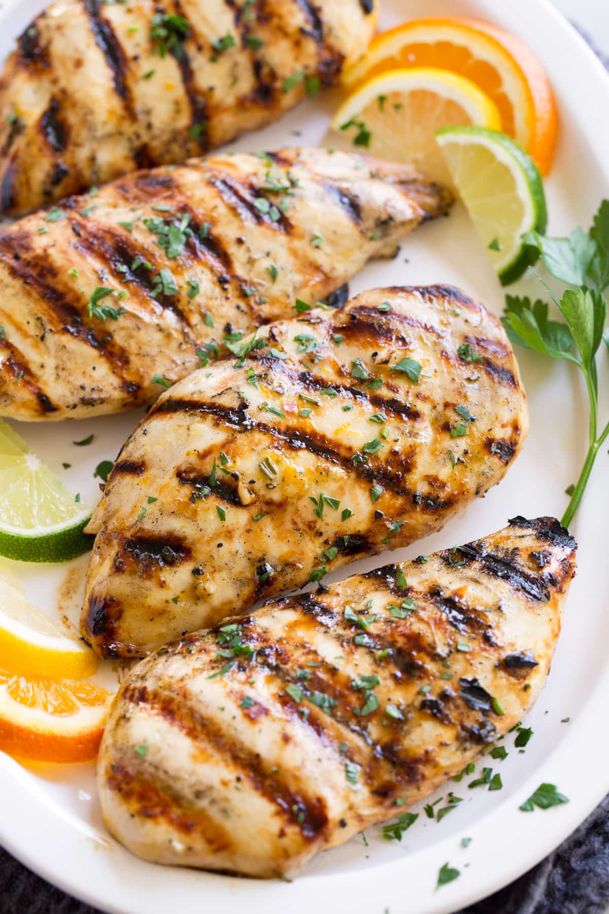 Row of marinated grilled chicken on a white serving plate.