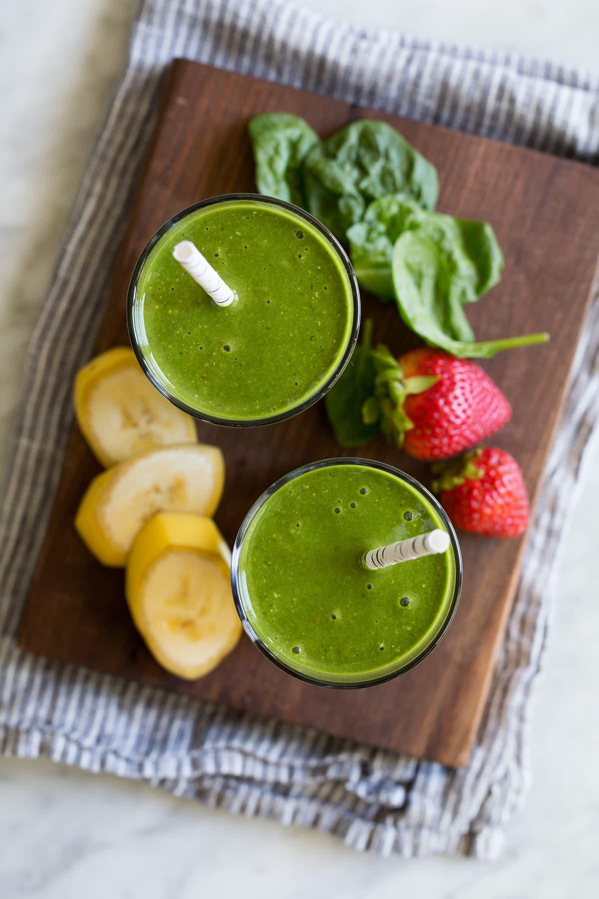 Overhead image of two glasses of green smoothies.
