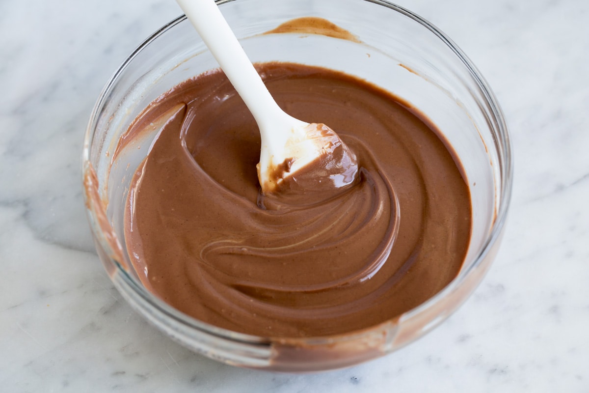 Melted chocolate peanut butter mixture in a glass mixing bowl with a spatula.