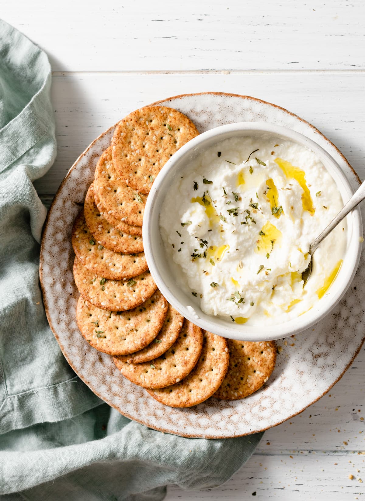 Easy homemade ricotta in a bowl with a side of crackers.