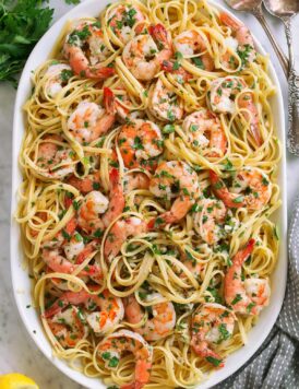 Shrimp scampi on a platter tossed with linguine pasta.