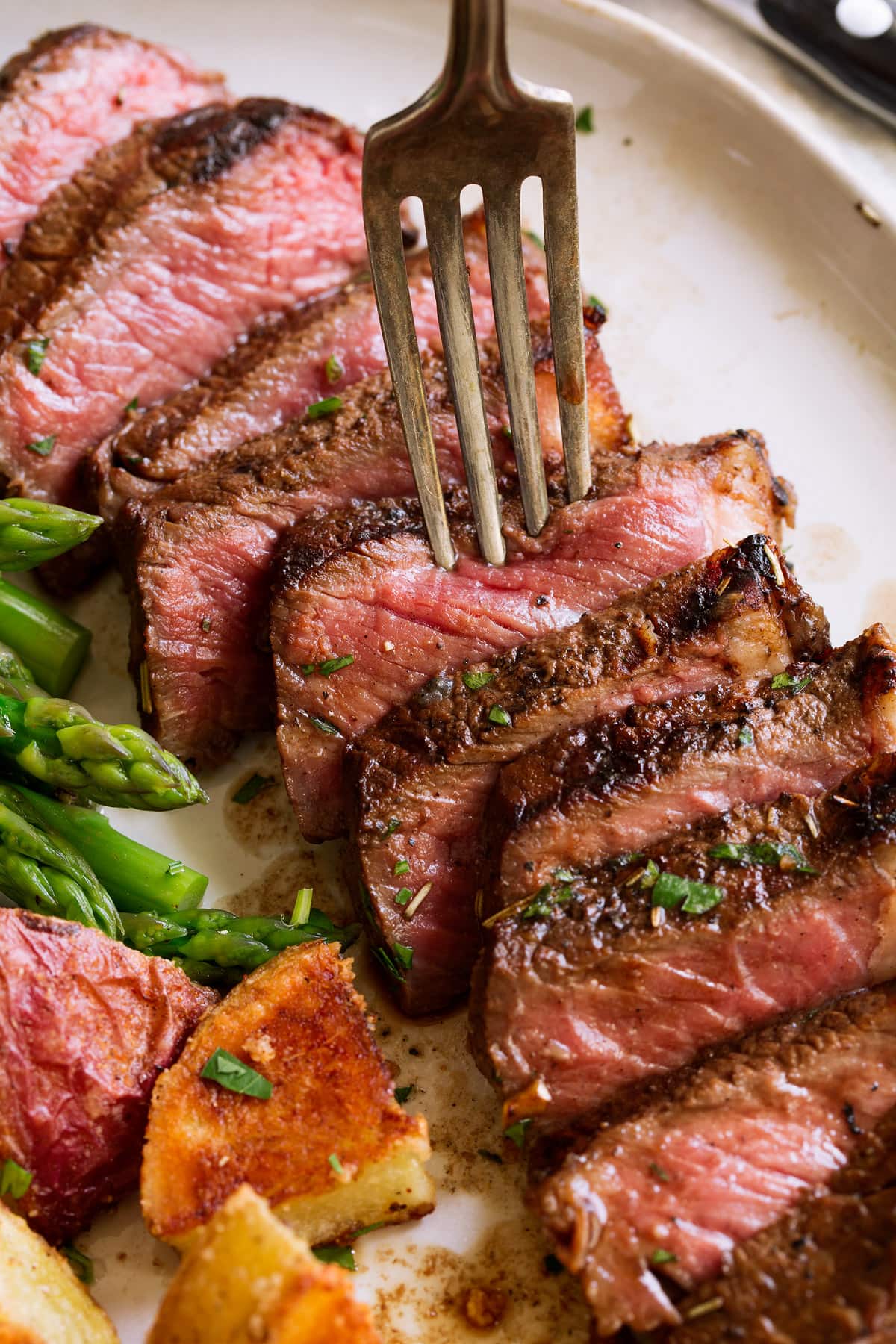 Close up image of sliced marinated steak with fork.
