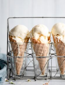 Three ice cream cones in a vintage wire and glass stand.