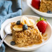 Slice of baked oatmeal topped with fresh fruit and maple syrup.