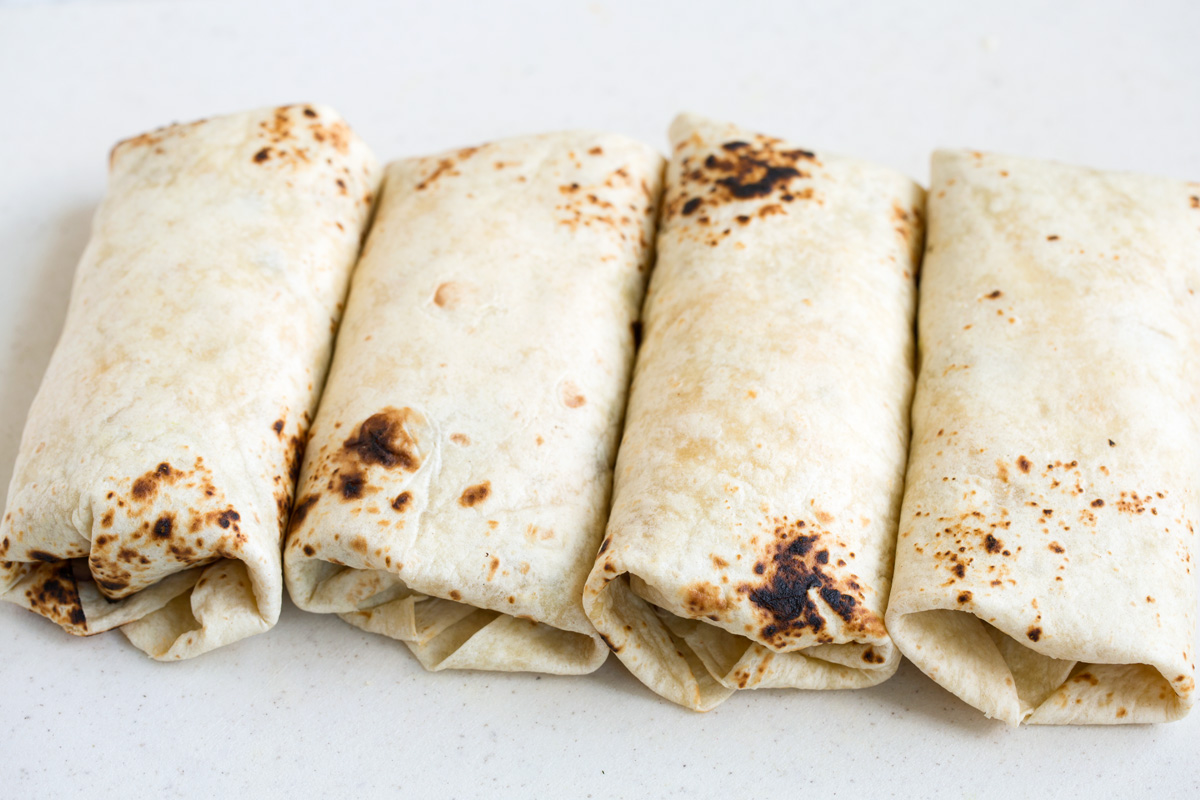 Four wrapped up breakfast burritos.
