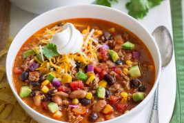 Two servings of taco soup in white bowls over a white platter.