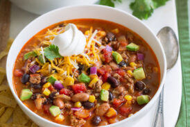 Two servings of taco soup in white bowls over a white platter.