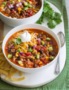Two servings of taco soup in white bowls over a white platter.
