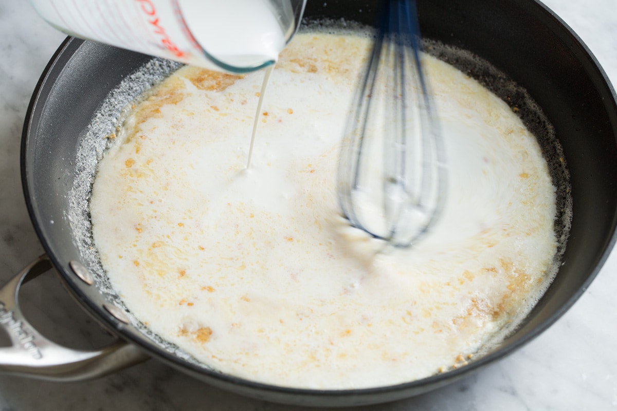 Whisking cream into flour and butter mixture in skillet.