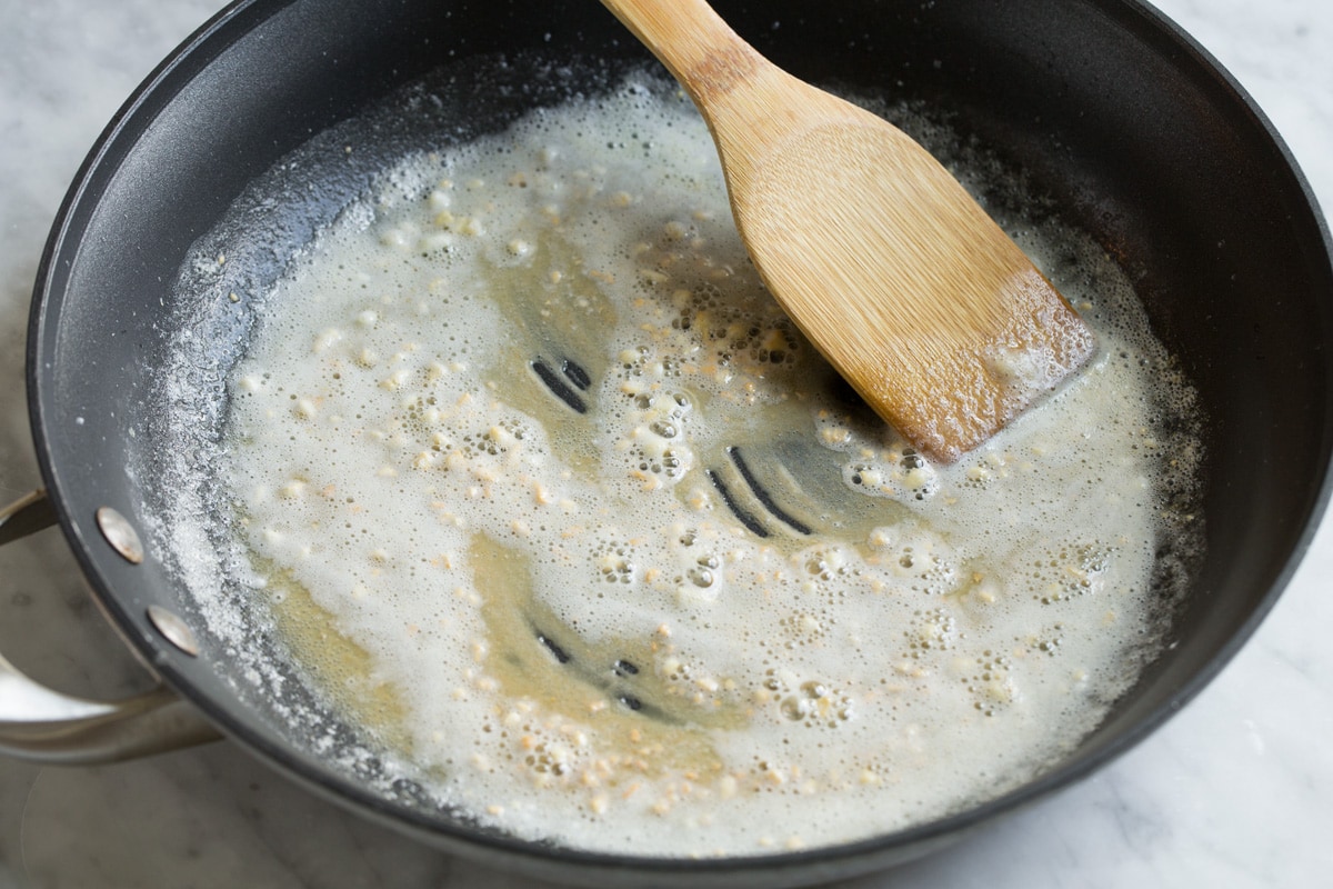 Sautéing flour and garlic in butter in a skillet.