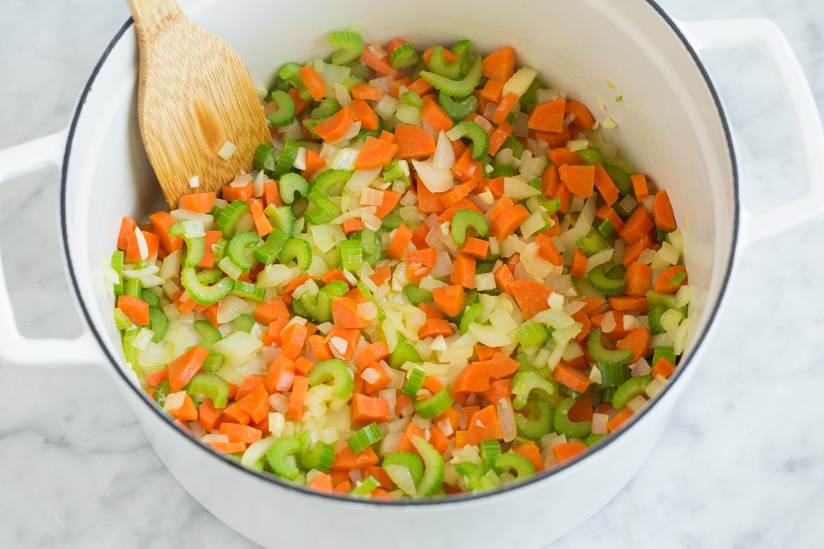Sauteing carrots, celery, onion and garlic in a pot.