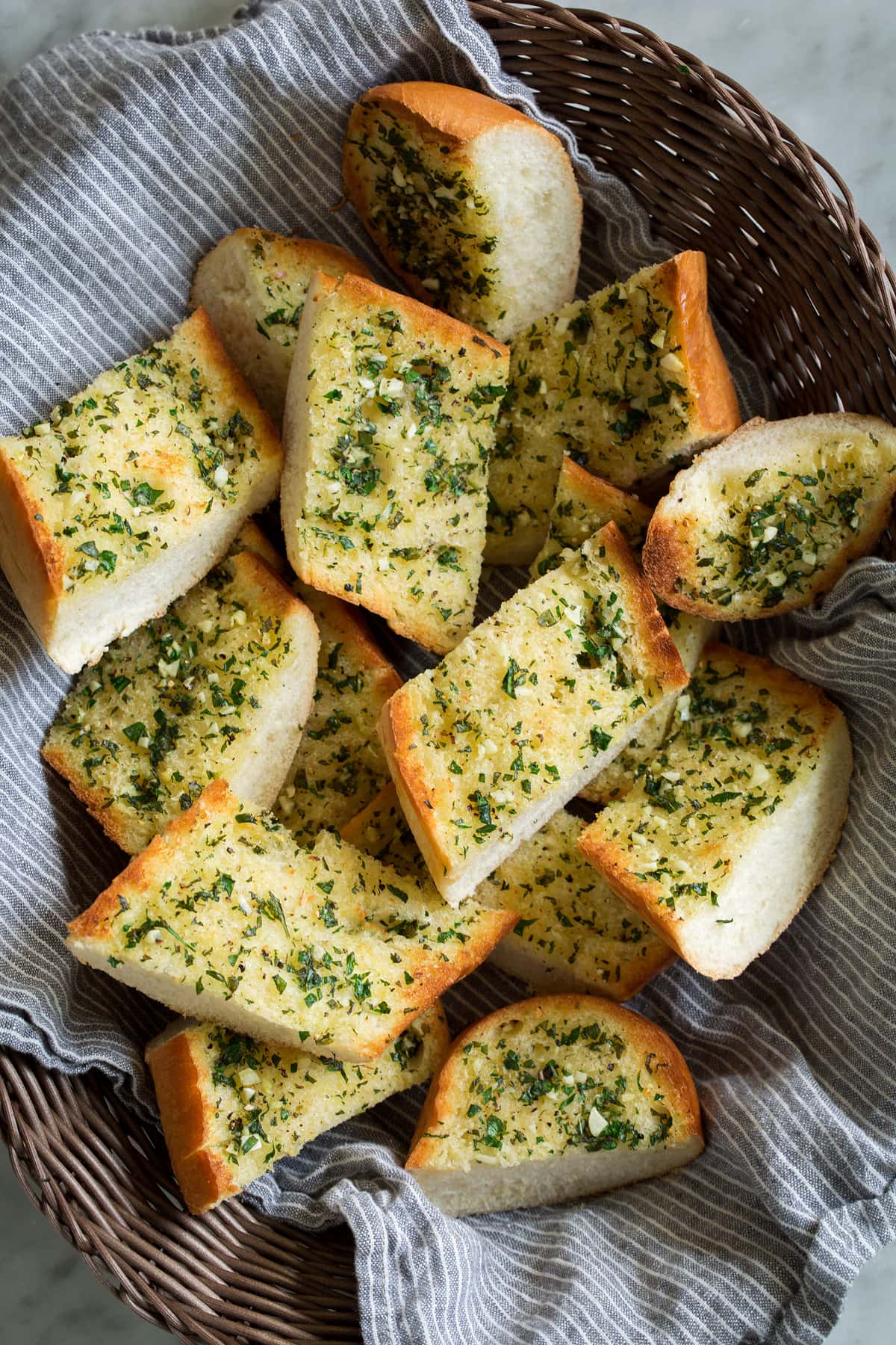 Garlic bread slices in a basket with a kitchen cloth.