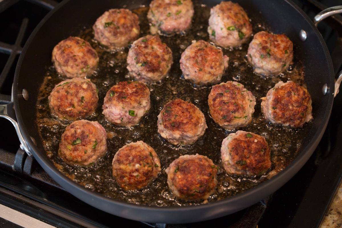 Meatballs cooked in a pan with olive oil.