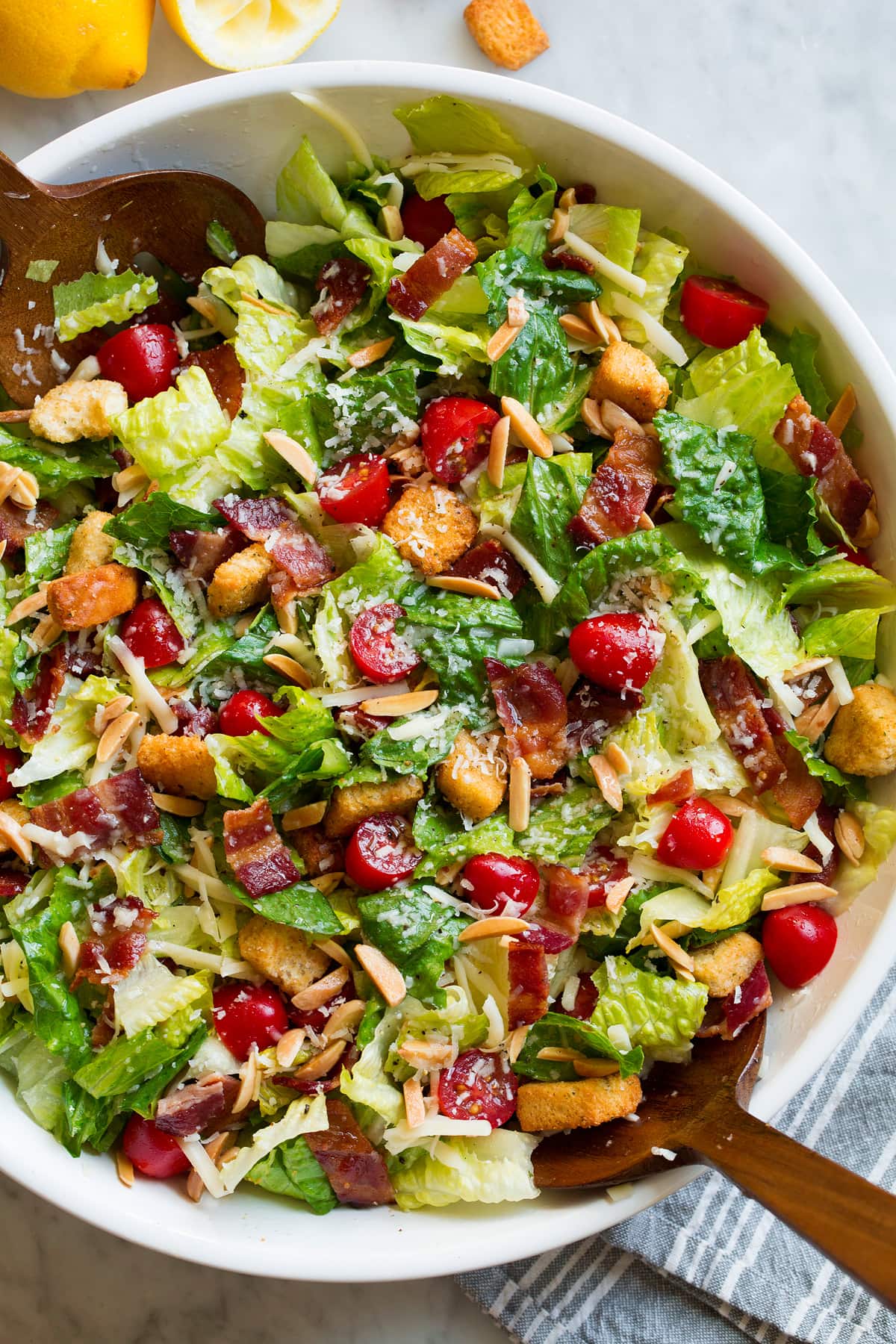 The Best Family Favorite Salad in a large salad bowl. Salad includes romaine lettuce, bacon, croutons, parmesan, swiss cheese, almonds, grape tomatoes and lemon vinaigrette dressing.