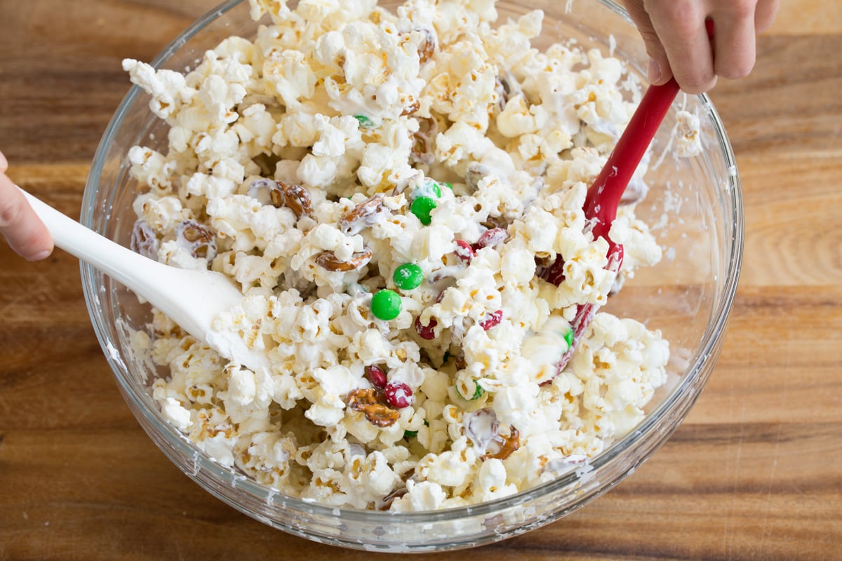 Tossing popcorn with melted white chocolate candy melts.