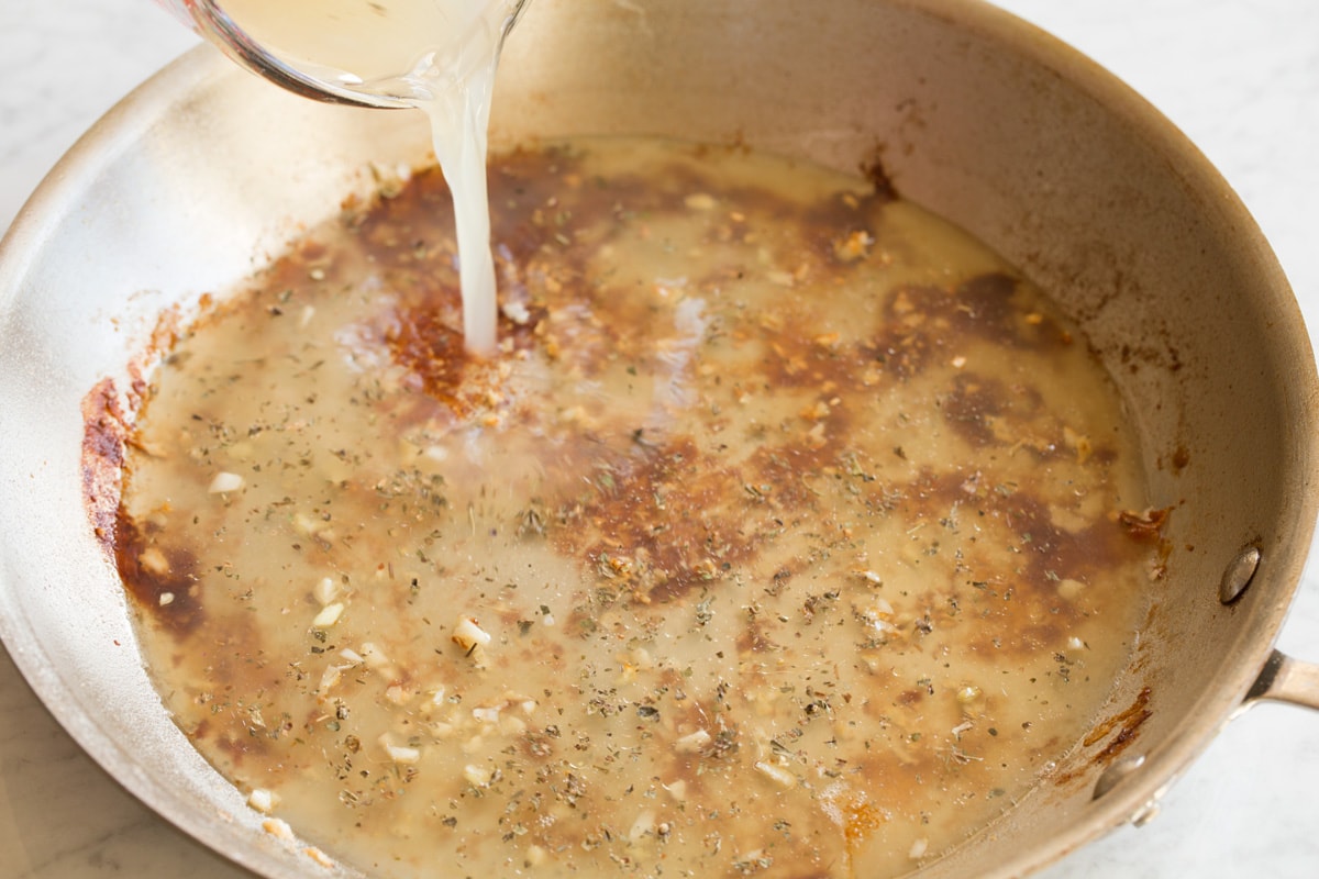 Pour chicken broth into skillet.