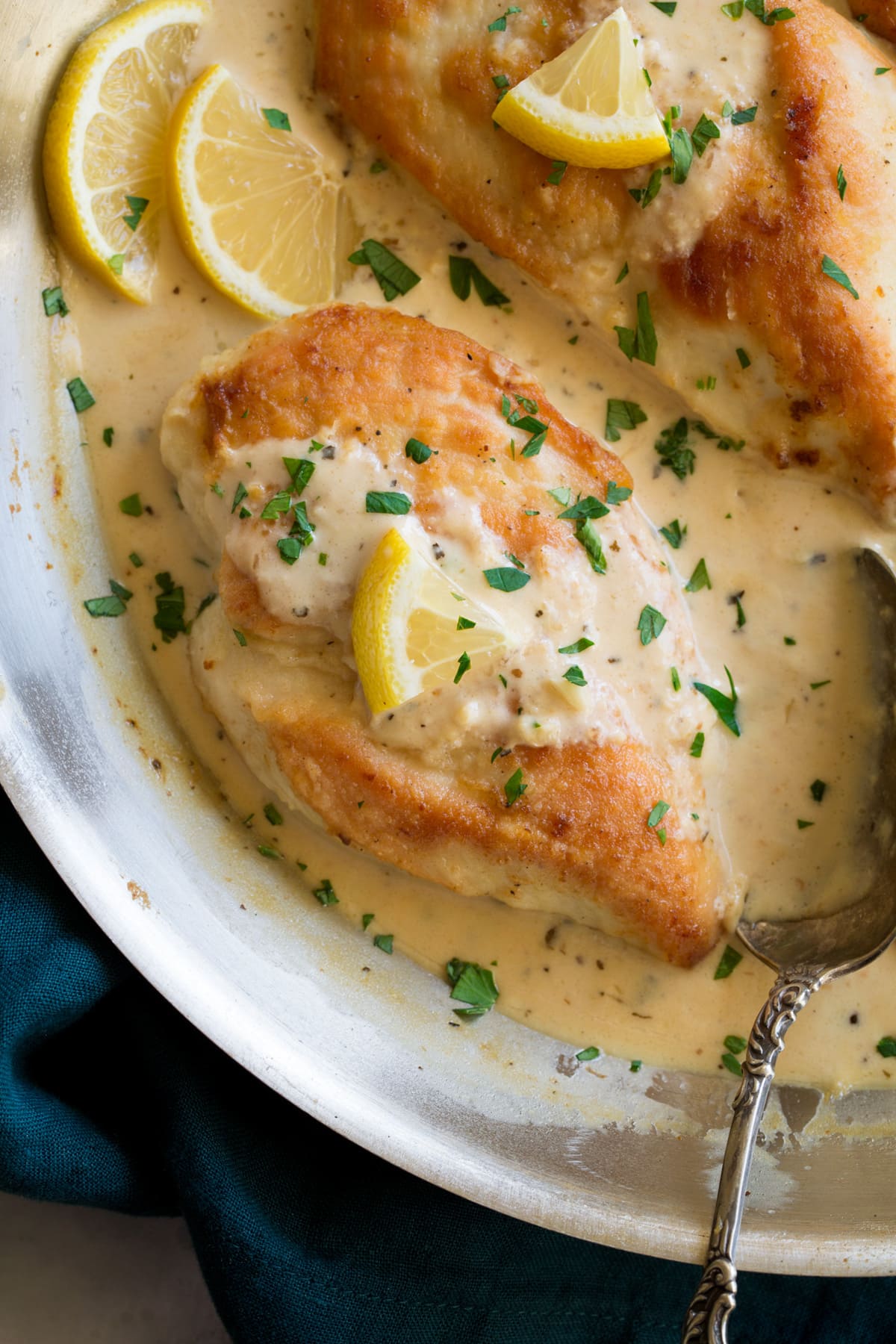 Close up image of chicken breasts in pan in a creamy lemon romano sauce.