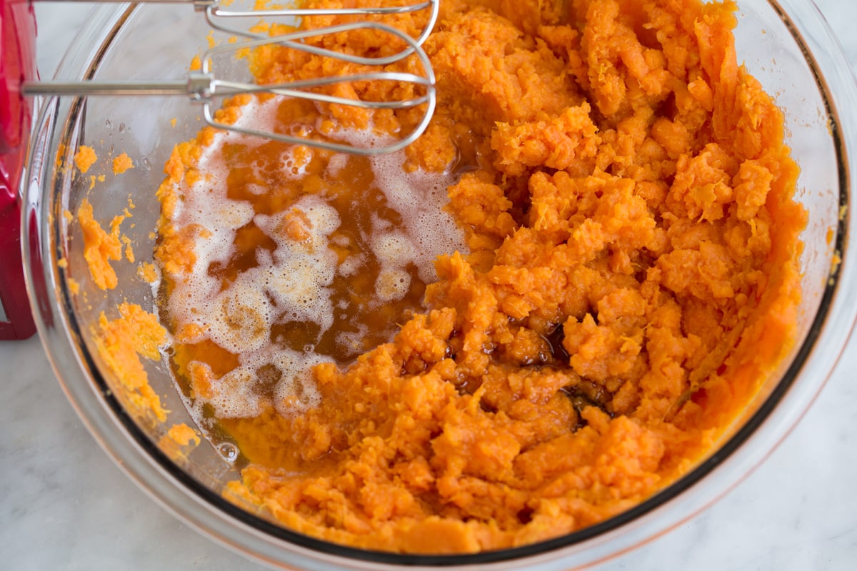 Adding browned butter and maple syrup to sweet potato mixture.