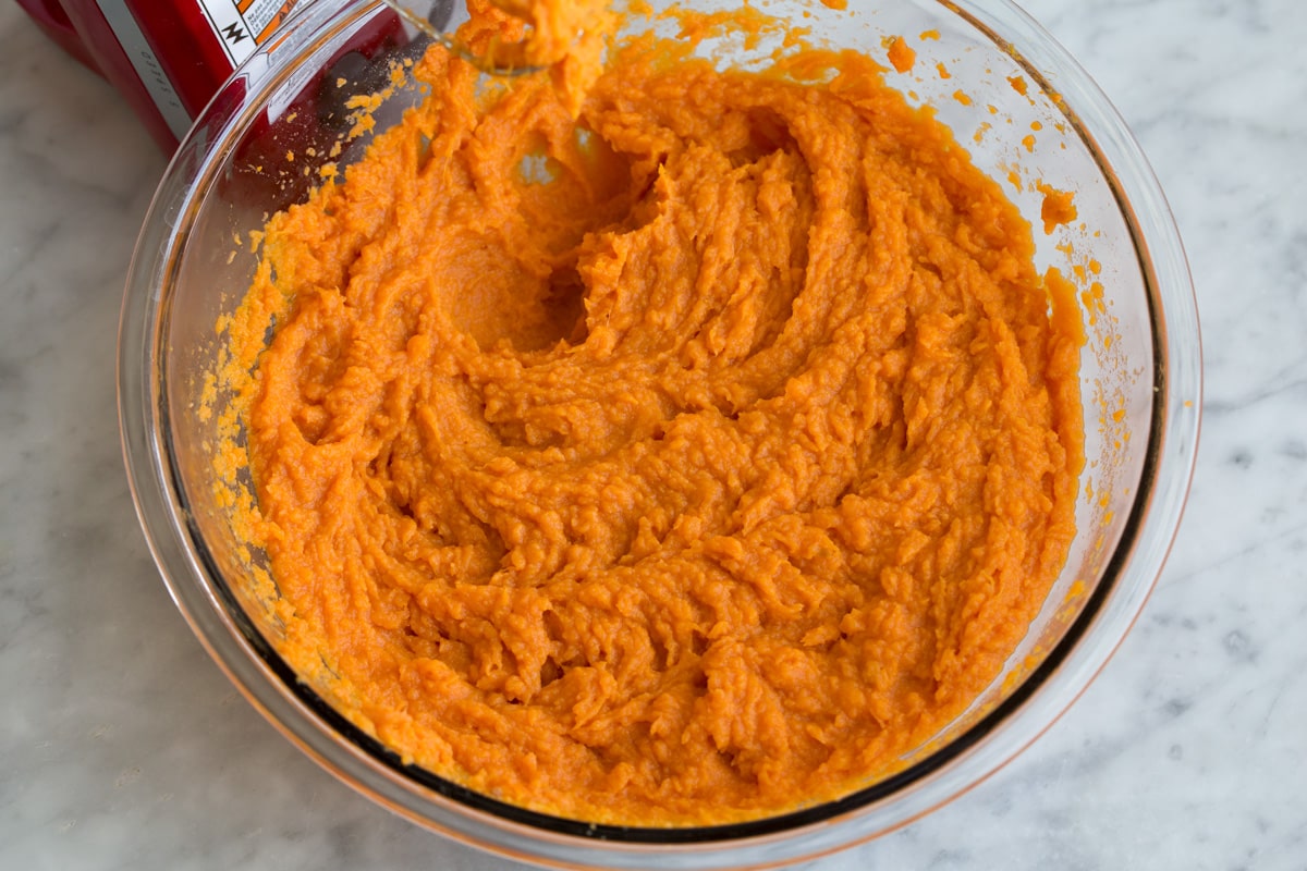 Mashed sweet potatoes shown after blending with an electric mixer.