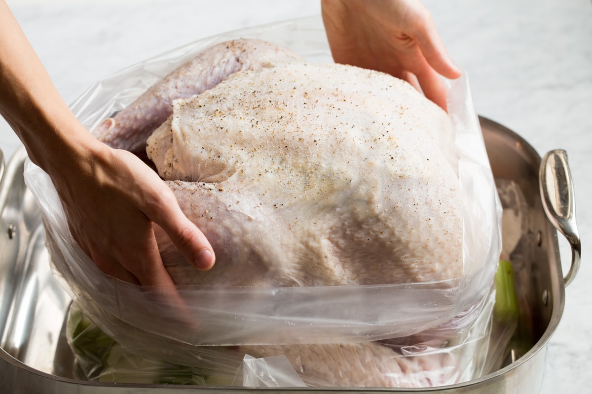 Putting turkey in an oven bag in a roasting pan.