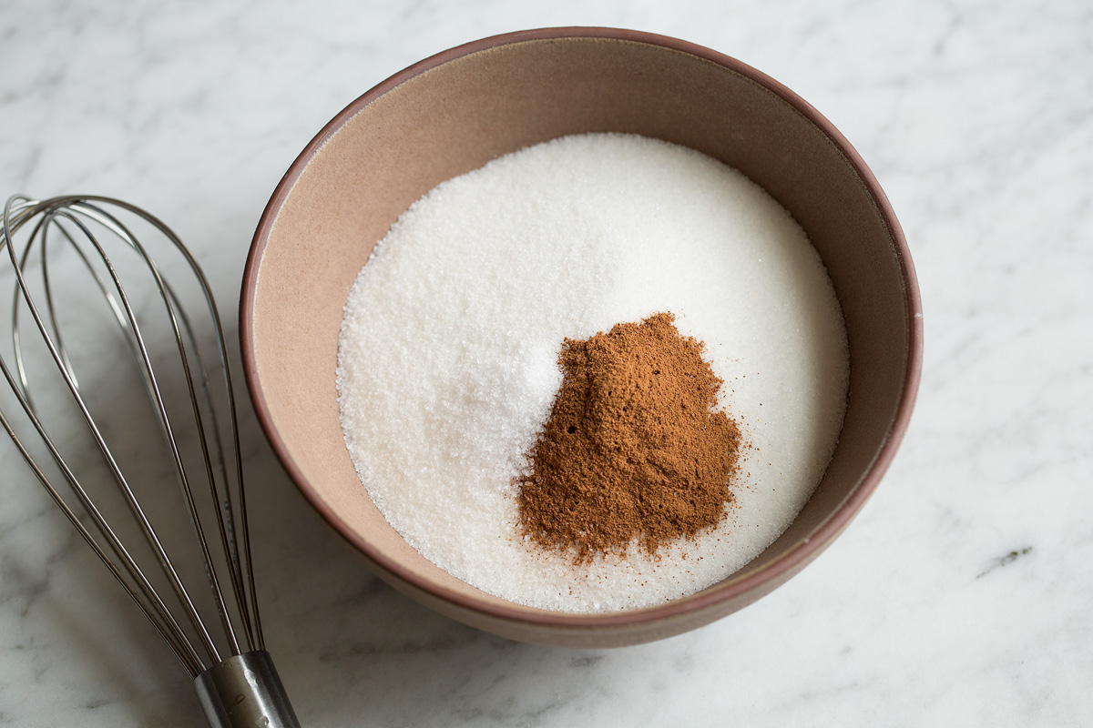 Mixing sugar and cinnamon in a bowl.