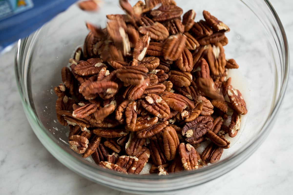 Pouring pecans into glass mixing bowl.