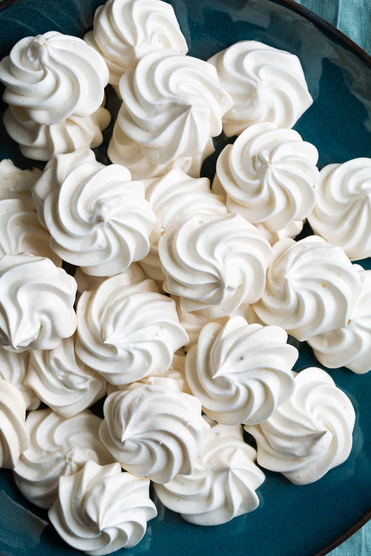 Close up image of meringue cookies on a large blue plate.