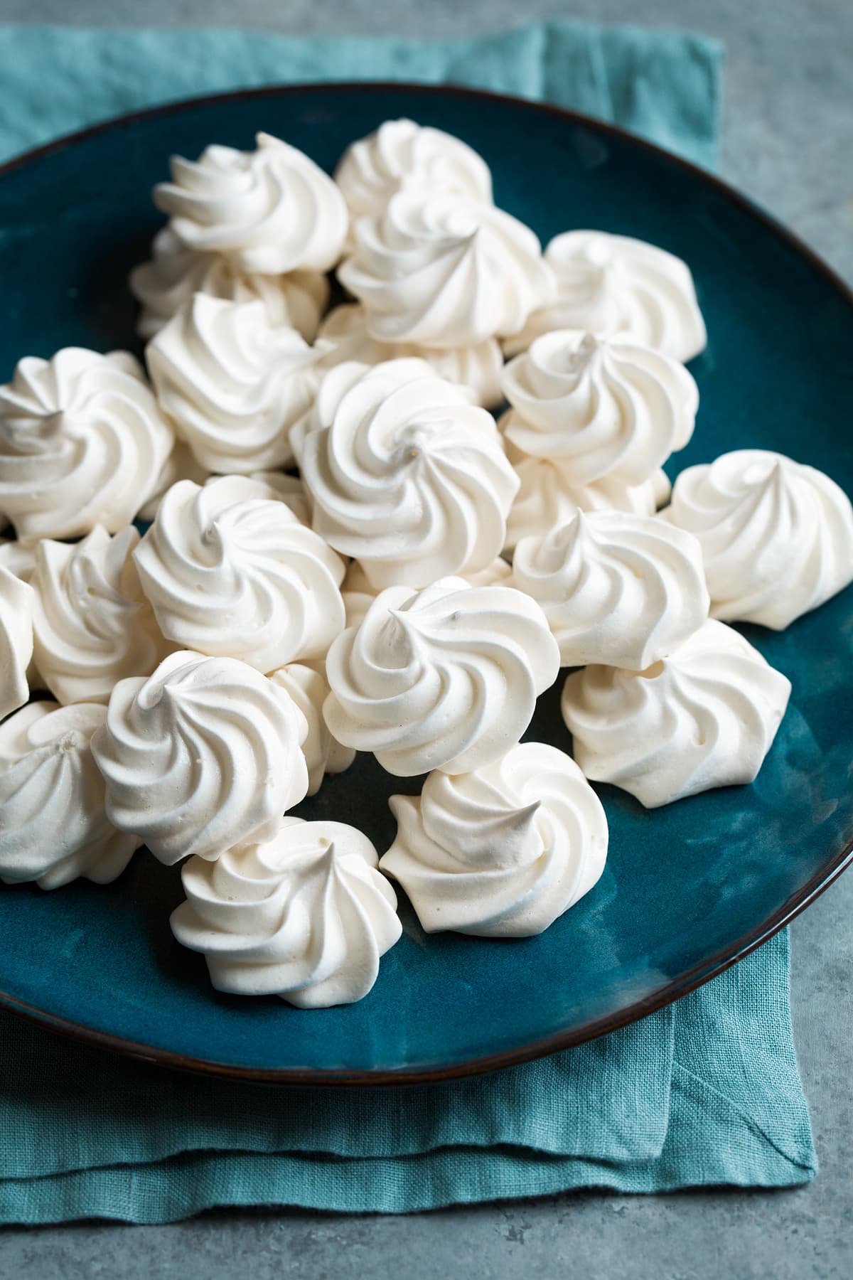 Round and swirly white meringue cookies on a large blue plate.