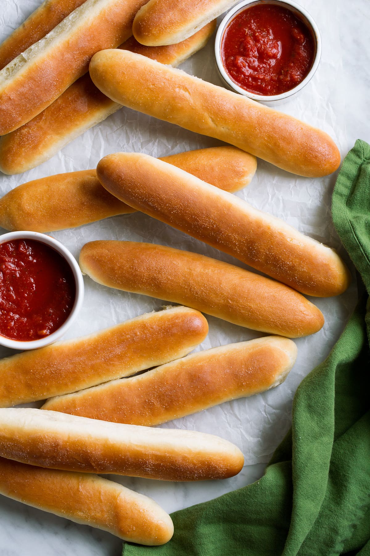 Breadsticks spread out onto parchment with sides of marinara sauce.