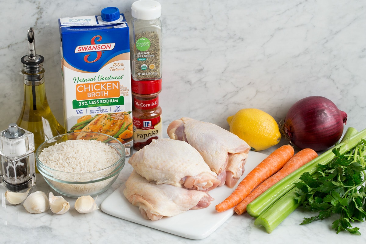 Image of ingredients used to make chicken and rice. Includes chicken thighs, rice, fresh vegetables, herbs, oil, lemon, garlic, salt and pepper.