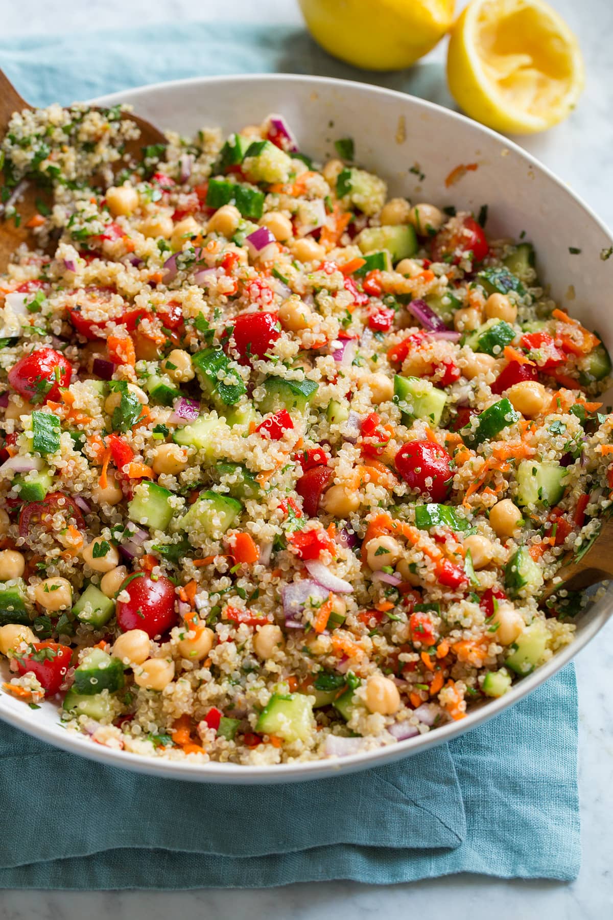 Healthy quinoa salad in a serving bowl. Salad shows quinoa, cucumber, tomatoes, carrots, red onion, chick peas and herbs.