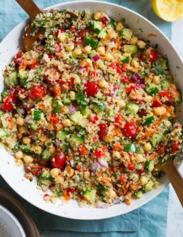 Quinoa Salad in a large serving bowl with wooden tongs on the side.