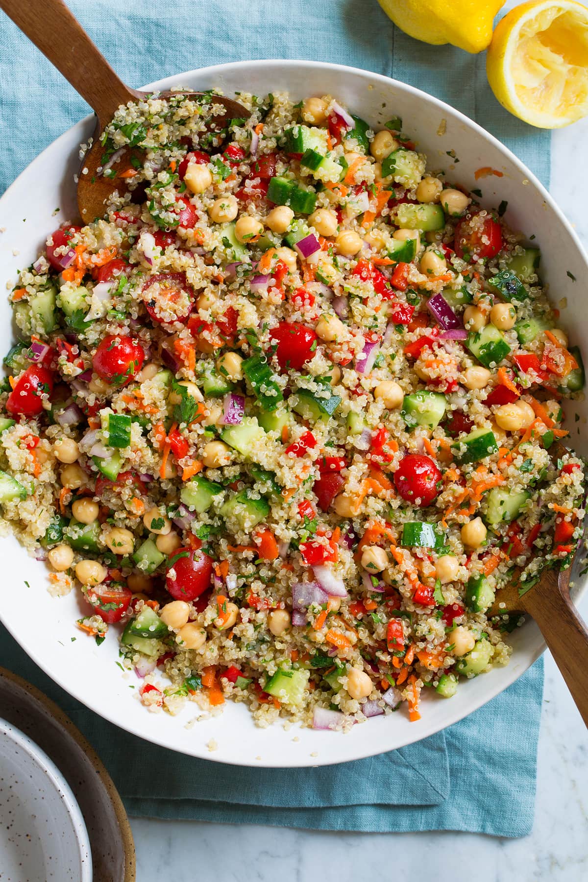 Quinoa Salad in a large serving bowl with wooden tongs on the side.
