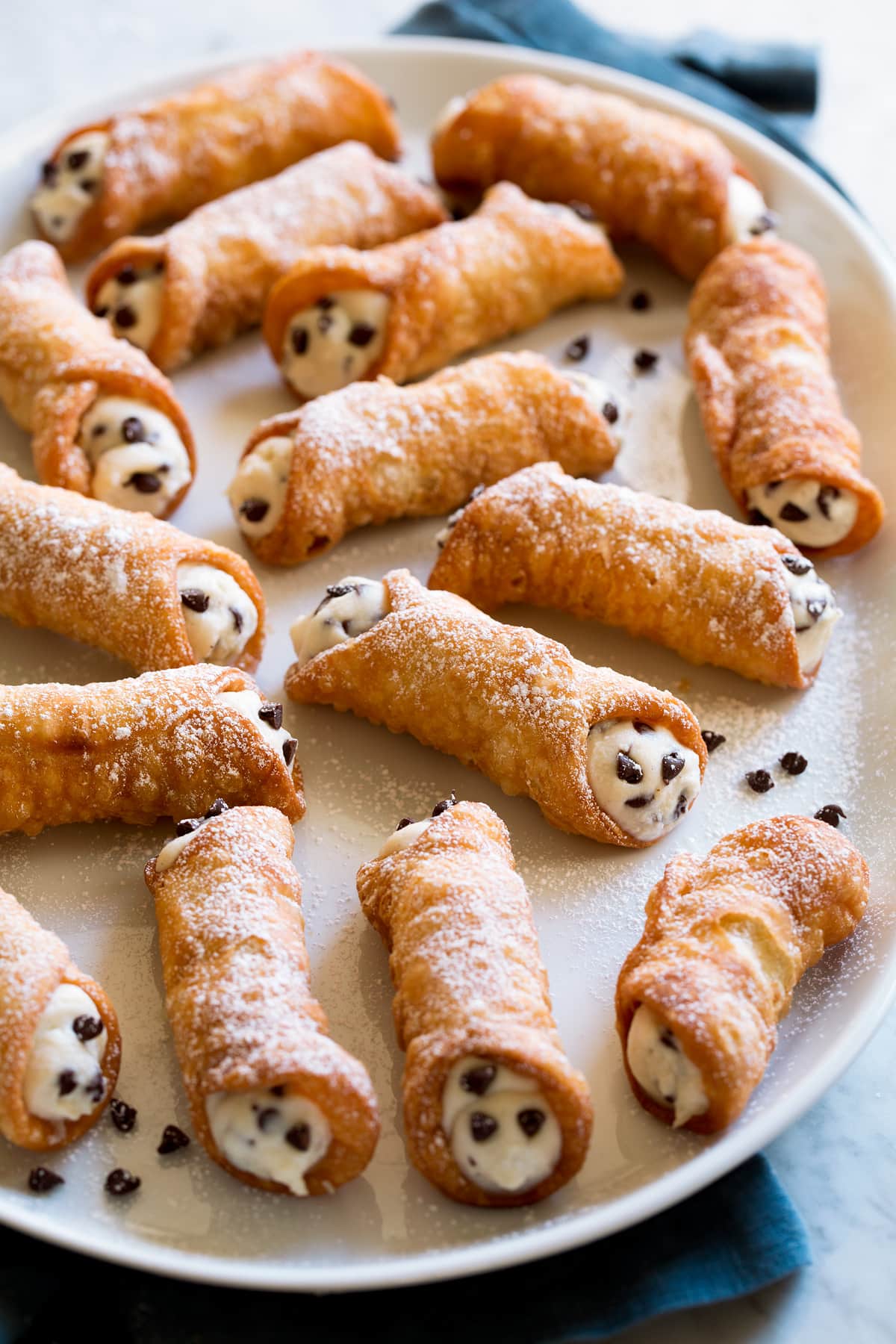 Cannoli with ricotta and chocolate chip filling on a white serving platter.