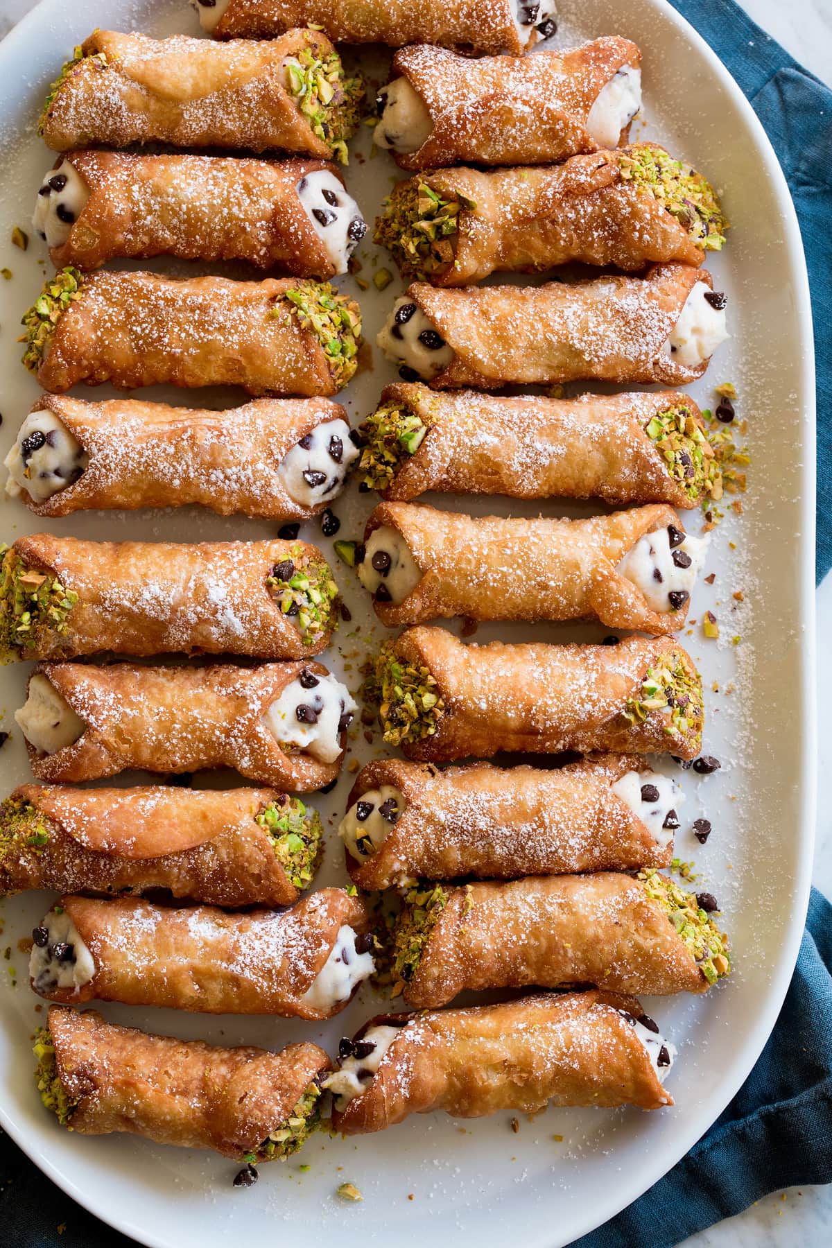 Overhead image of two rows of homemade ricotta filled cannoli on a serving platter.