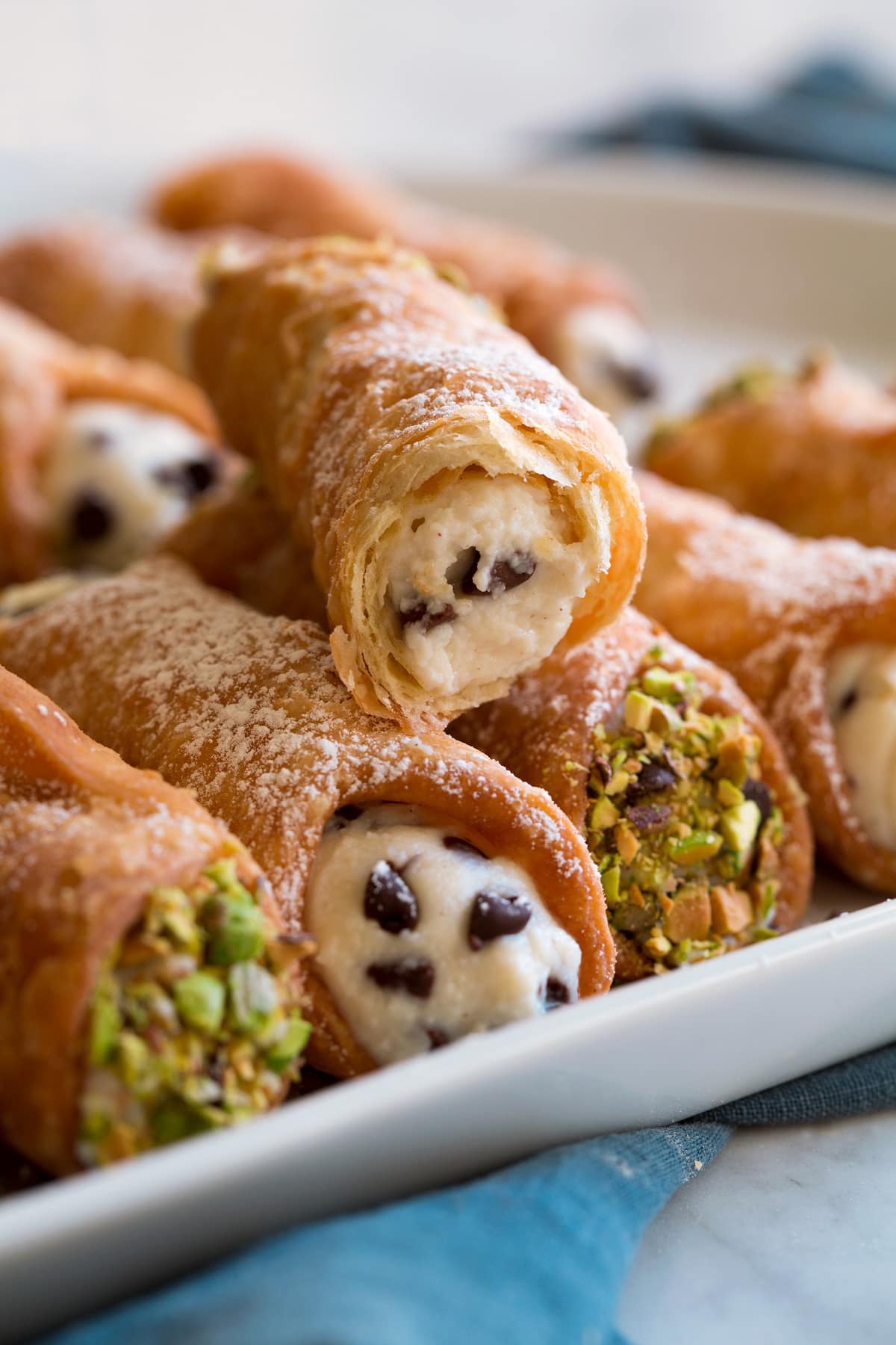 Cannoli bitten into to show flaky layers and crispy texture along with ricotta and chocolate chip filling.