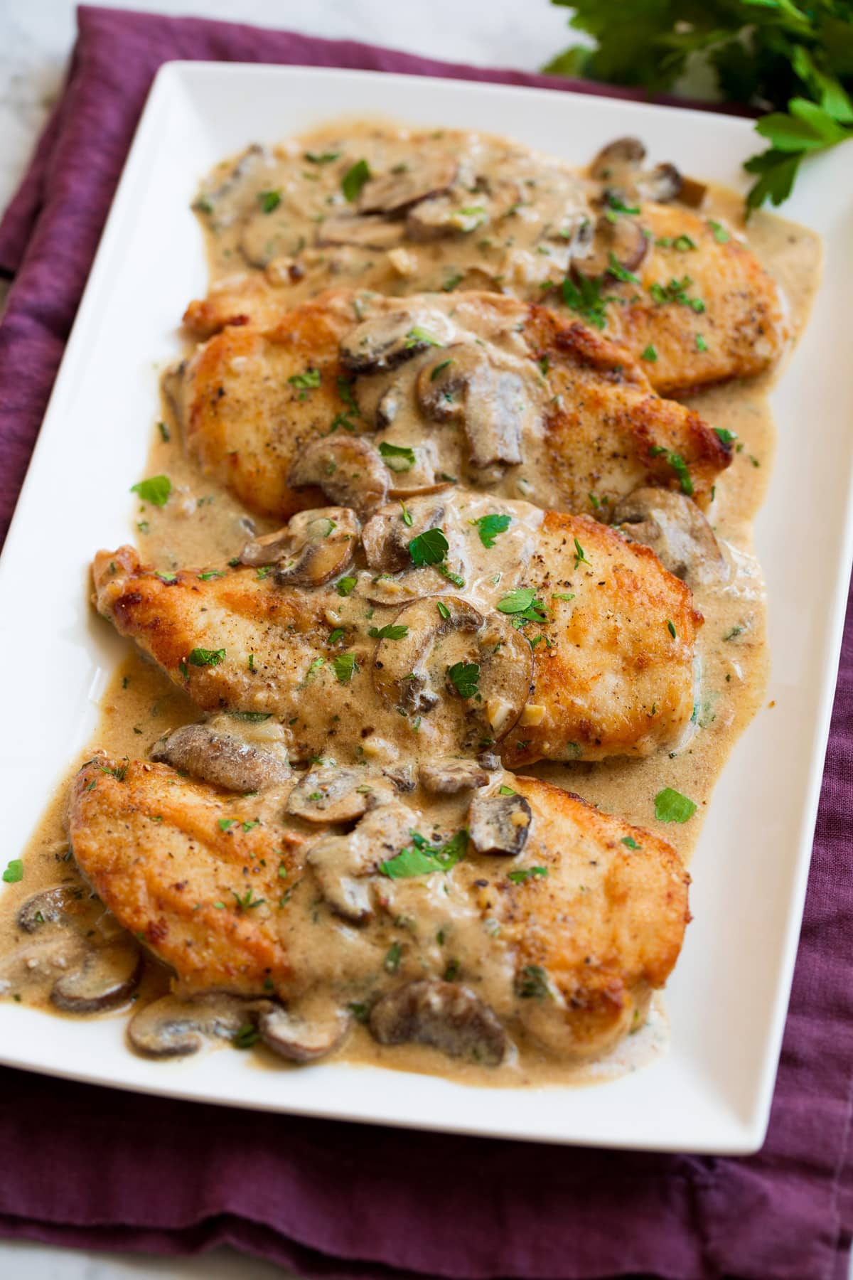 Chicken marsala on a white serving platter. Showing four servings.